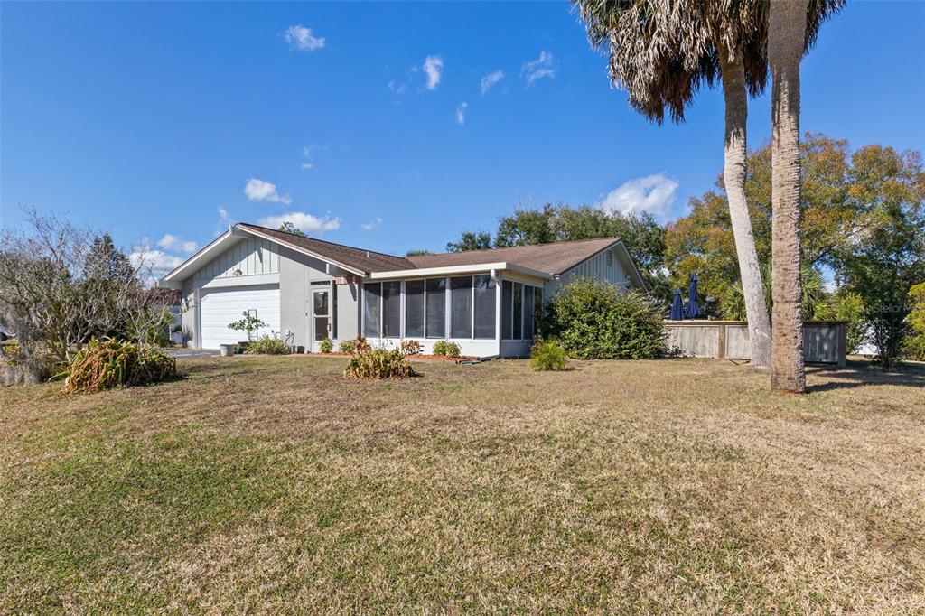 A single-story house with a white garage, a screened-in porch, and palm trees — 15 CLARK LANE, PALM COAST, FL