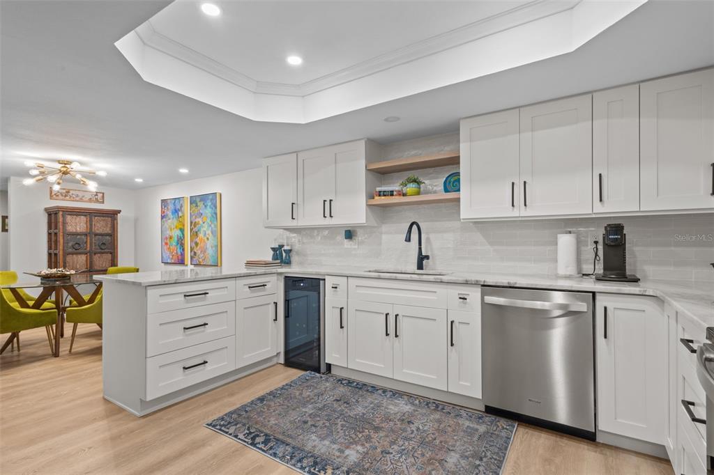 A kitchen features white shaker cabinets, stainless steel appliances, a marble countertop, and a rug — 3021 COUNTRYSIDE BOULEVARD UNIT 21A, CLEARWATER, FL