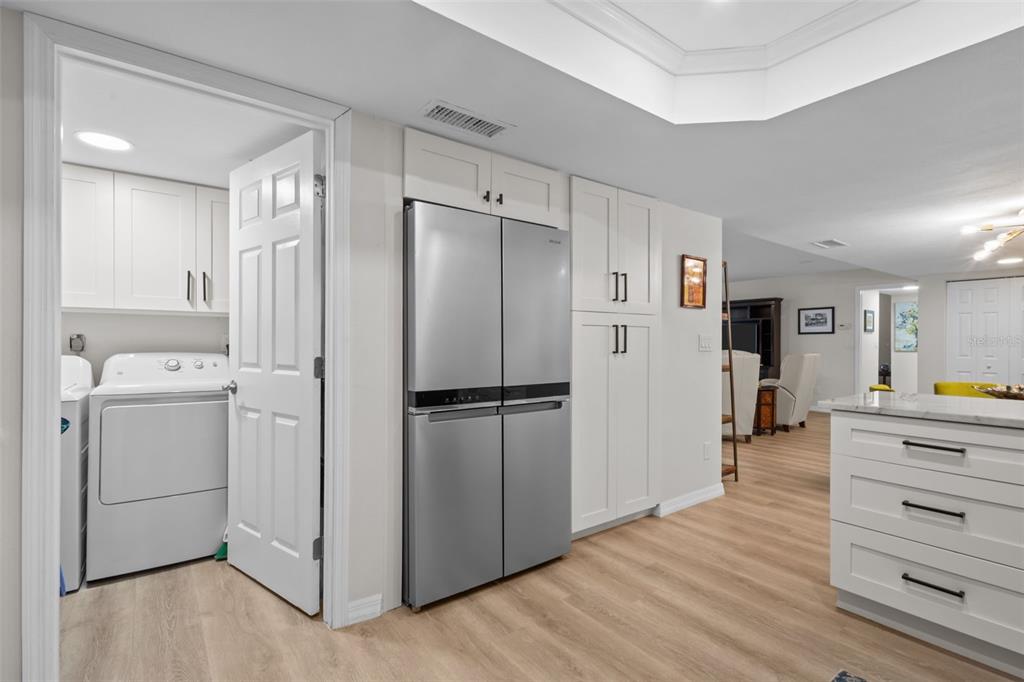 A kitchen with white cabinetry, a stainless steel refrigerator, and an adjacent laundry room — 3021 COUNTRYSIDE BOULEVARD UNIT 21A, CLEARWATER, FL