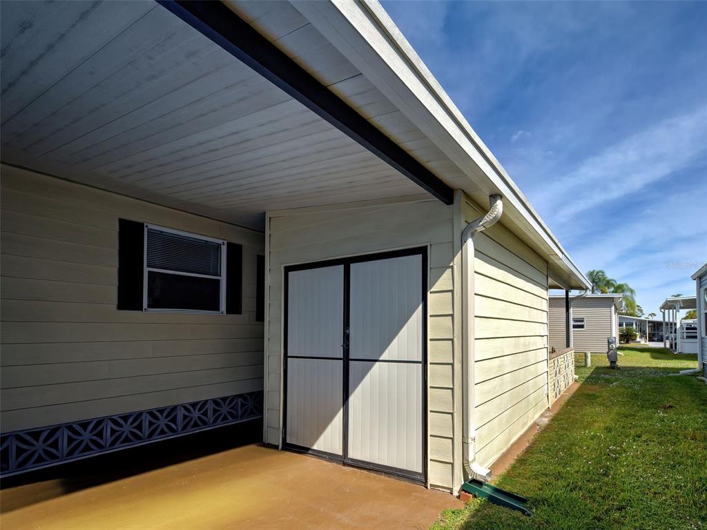 A beige exterior storage shed is attached to the side of a mobile home — 2100 KINGS HIGHWAY UNIT 1067, PORT CHARLOTTE, FL