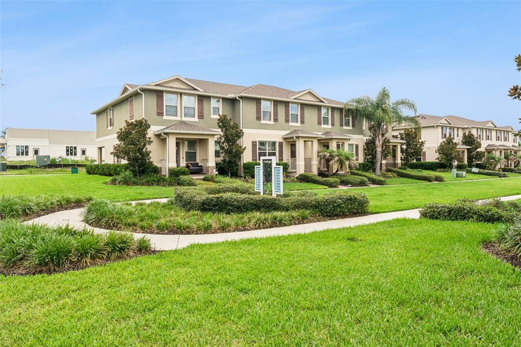 A multi-unit residential building with tan siding and a green lawn in the foreground — 9991 SCHROEDER ALLEY, WINTER GARDEN, FL