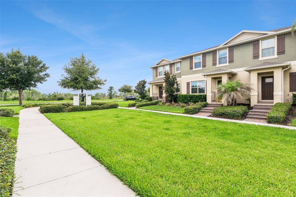 A row of two-story townhomes with green lawns and a concrete sidewalk in the foreground — 9991 SCHROEDER ALLEY, WINTER GARDEN, FL