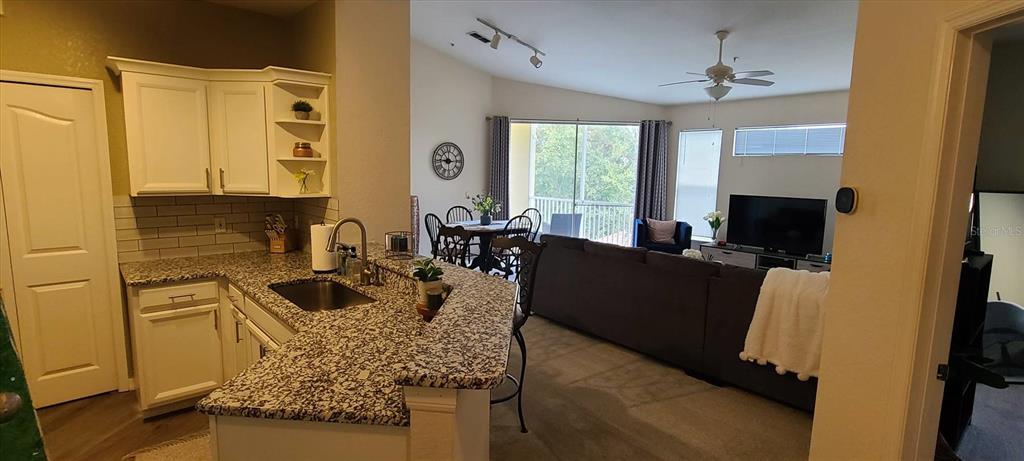 A kitchen with granite countertops overlooks an open-concept living and dining area — 1475 LAKE SHADOW CIRCLE UNIT 6307, MAITLAND, FL