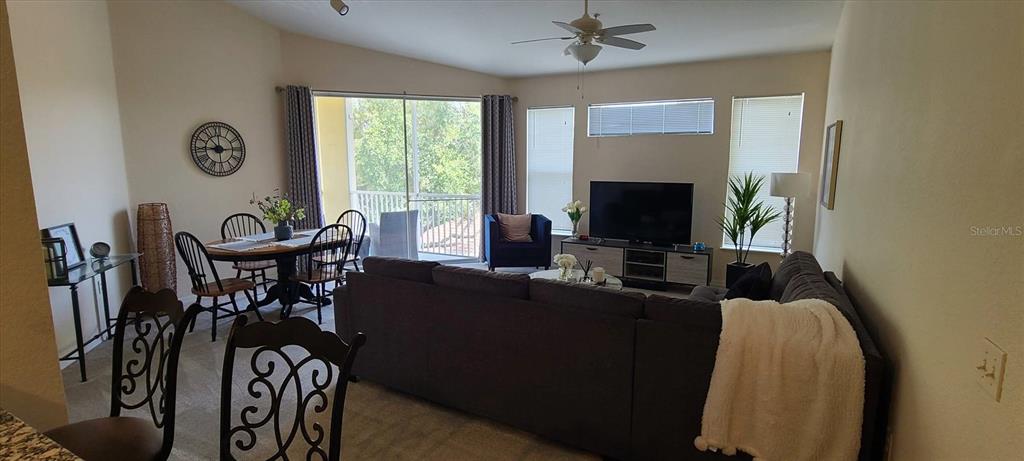 A living room and dining area feature a large sectional sofa, television, and balcony access — 1475 LAKE SHADOW CIRCLE UNIT 6307, MAITLAND, FL