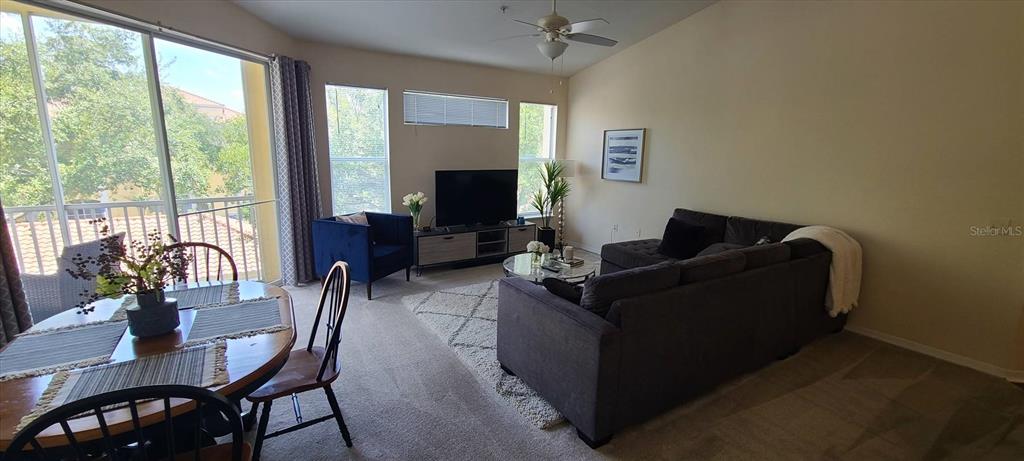 A living and dining area features a sectional sofa, television, and large sliding glass doors — 1475 LAKE SHADOW CIRCLE UNIT 6307, MAITLAND, FL