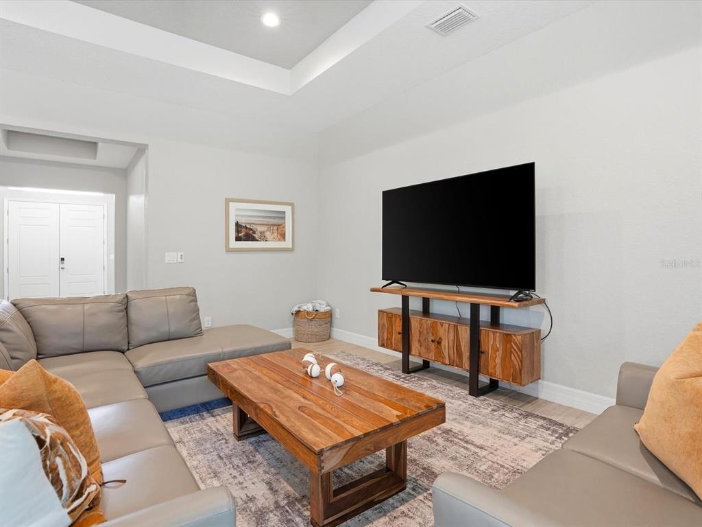 A living room features a grey sectional sofa, a wooden coffee table, and a television console — 776 ROTONDA CIRCLE, ROTONDA WEST, FL