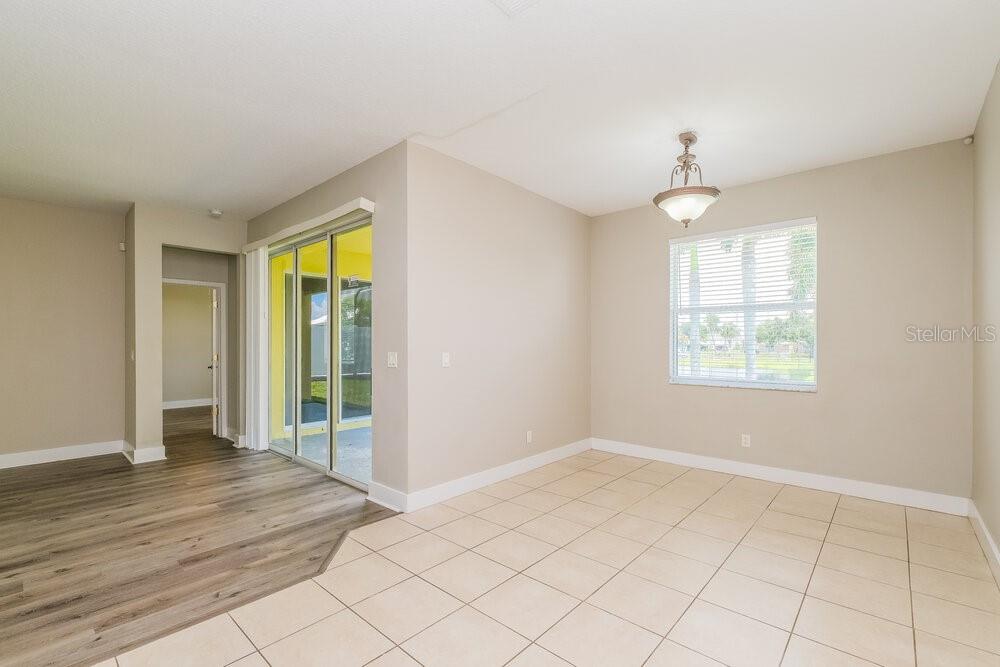 A dining area features beige tile flooring, a light fixture, and sliding glass patio doors — 569 BIMINI BAY BOULEVARD, APOLLO BEACH, FL