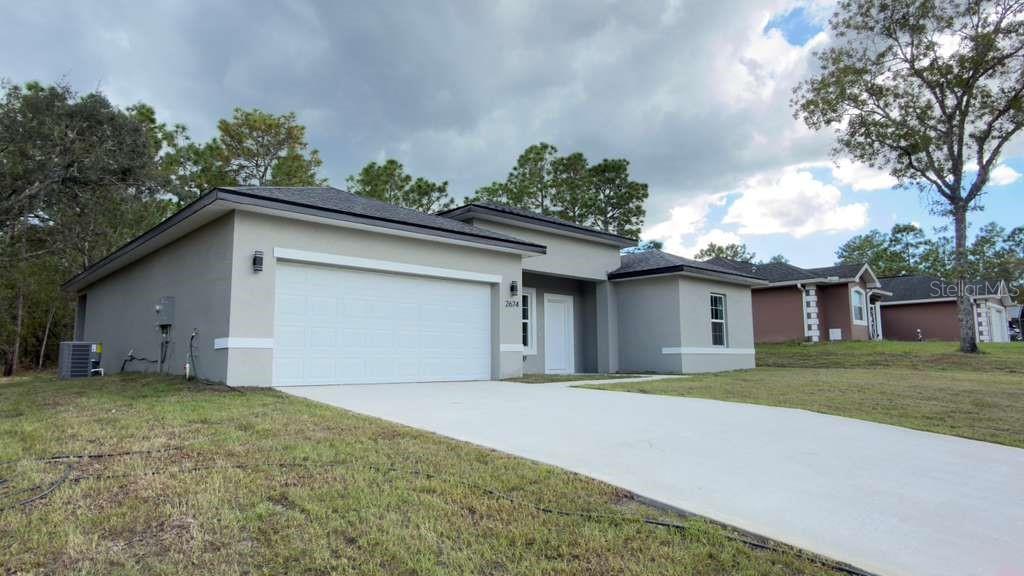 A modern, single-story stucco house with a two-car garage and a concrete driveway — 2674 W PINTADO DRIVE, CITRUS SPRINGS, FL