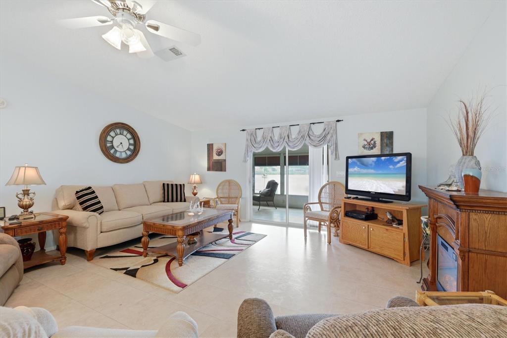 A living room features a beige sofa, a wooden coffee table, and a sliding glass door — 8479 GULL DRIVE, ENGLEWOOD, FL