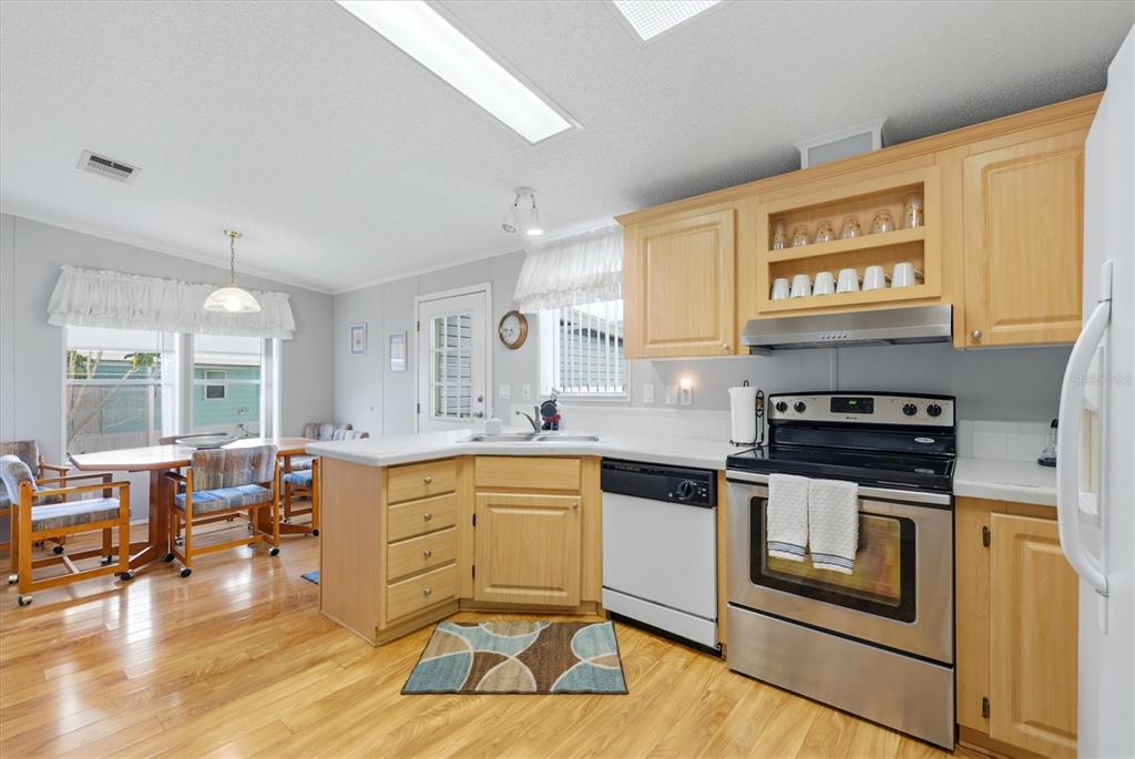 A kitchen with light wood cabinets, stainless steel appliances, and an adjacent dining area — 8479 GULL DRIVE, ENGLEWOOD, FL