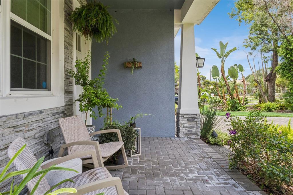 A covered front porch features stone veneer siding, brick pavers, and two rocking chairs — 980 BURNS STREET, ORLANDO, FL