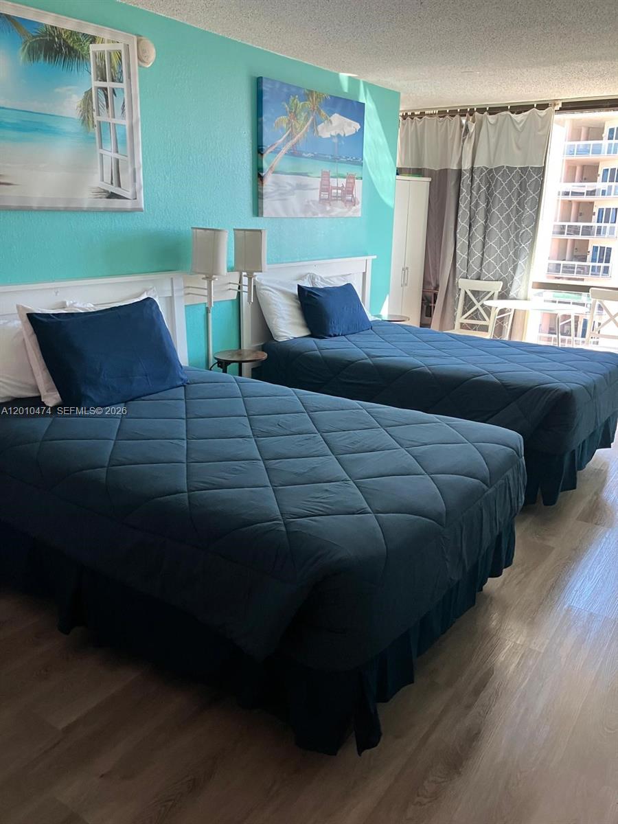 A bedroom features two beds with navy blue bedding against a bright turquoise wall — 1909 S Atlantic Ave # 804, Daytona FL 33118, DAYTONA, FL