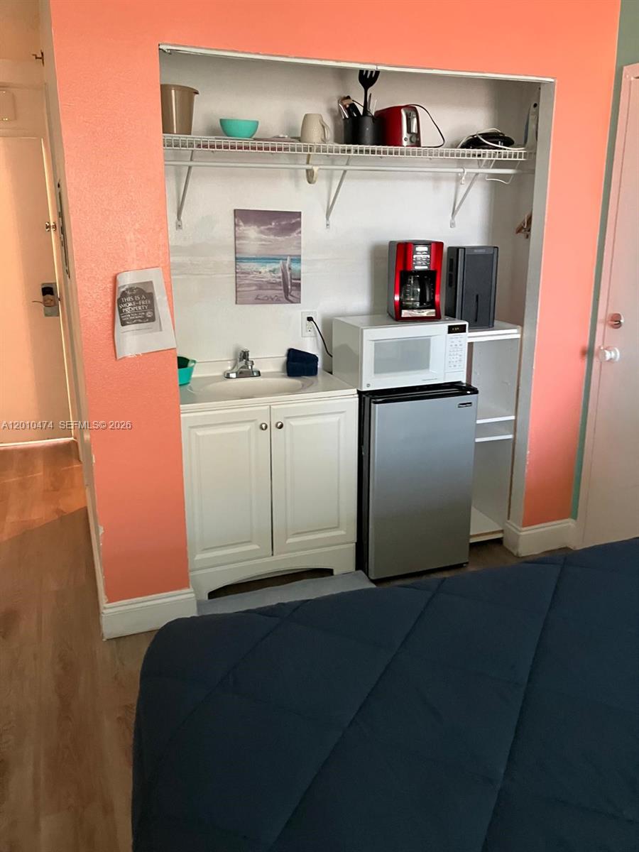 A small kitchenette area features a sink, microwave, mini-fridge, and open shelving against peach walls — 1909 S Atlantic Ave # 804, Daytona FL 33118, DAYTONA, FL