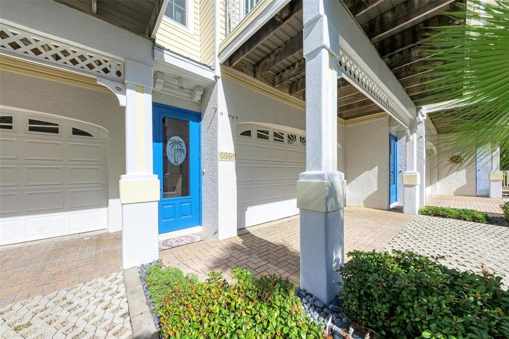 The exterior view shows a covered entryway with two garage doors and a blue door — 1469 GULF DRIVE N, BRADENTON BEACH, FL