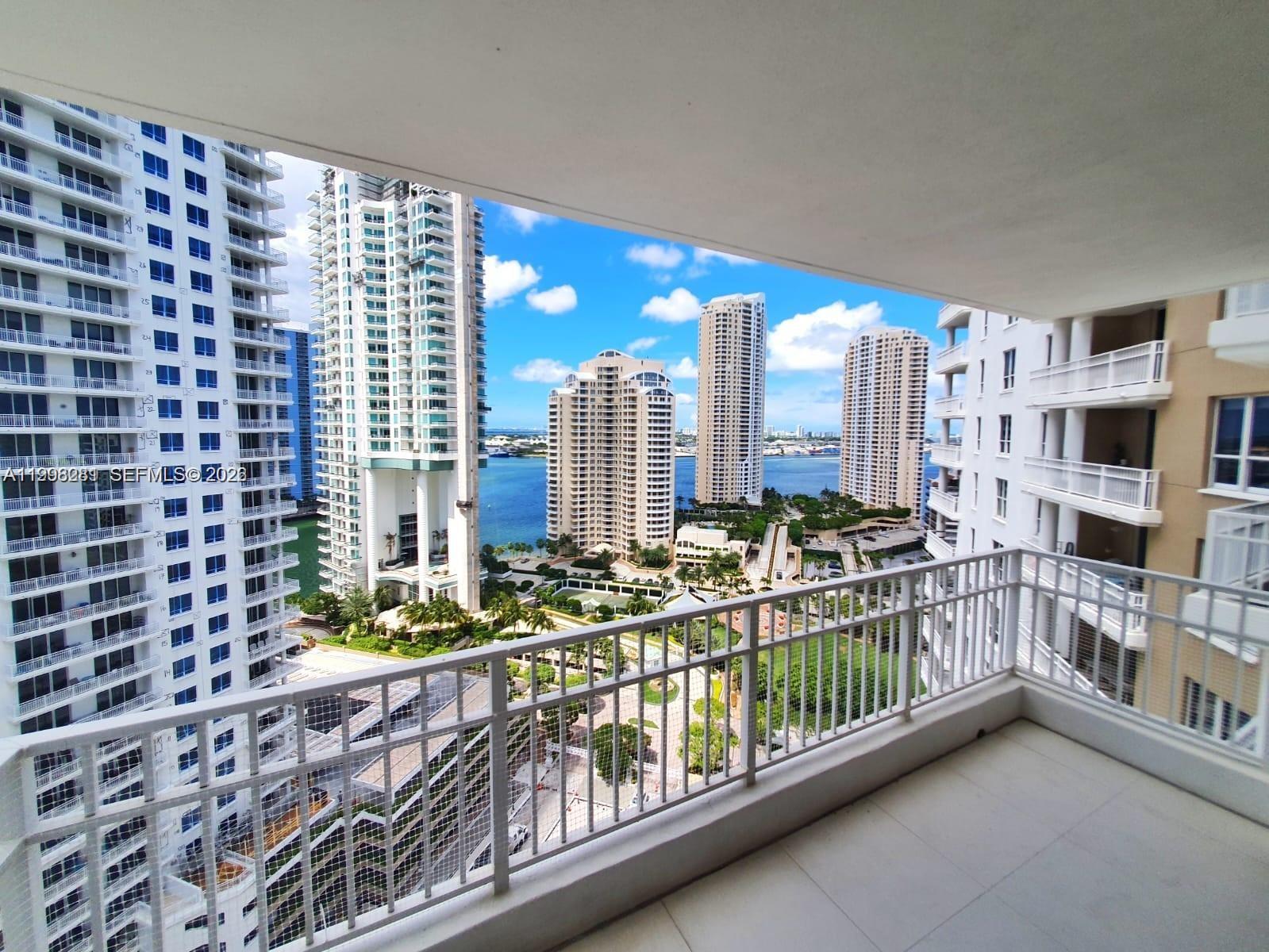 A balcony with a white railing overlooks a waterfront view of several high-rise buildings — 701 Brickell Key Blvd # 2306, Miami FL 33131, MIAMI, FL