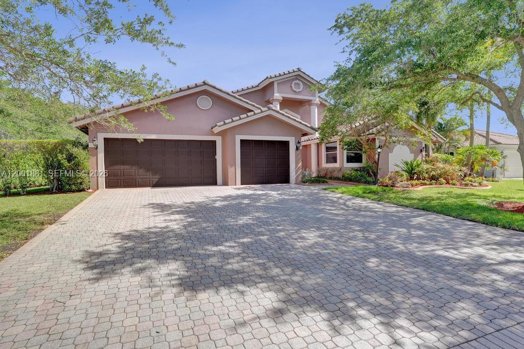 A two-story house with a three-car garage and a paved driveway under a clear sky — 9921 NW 60th Pl, Parkland FL 33076, PARKLAND, FL