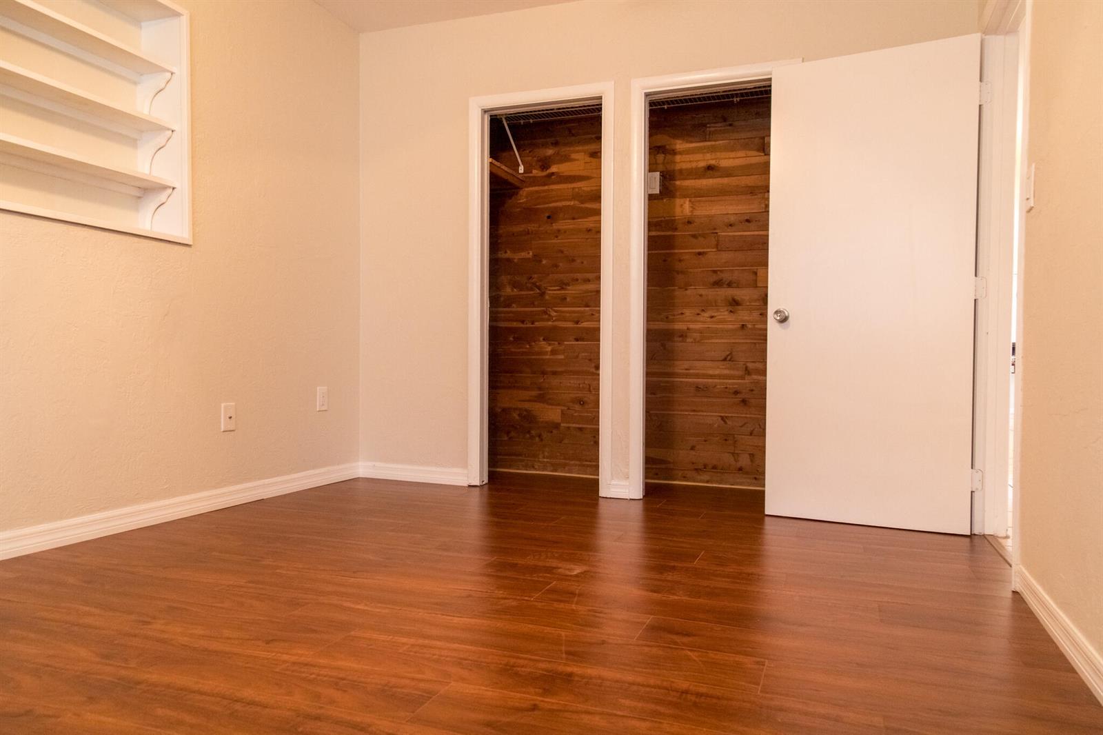 A bedroom features wood-look flooring, a built-in wall shelf, and two closets with cedar lining — 130 SW 14th Avenue, Boynton Beach FL 33435, BOYNTON BEACH, FL