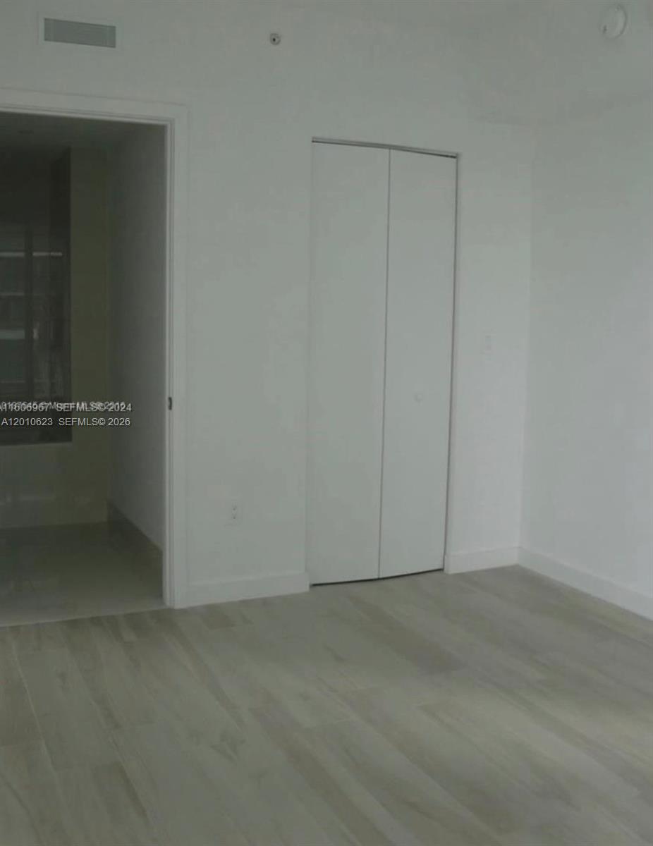 A room with light wood-look flooring, white walls, and a white bi-fold closet door — 1300 S Miami Ave # 1908, Miami FL 33130, MIAMI, FL