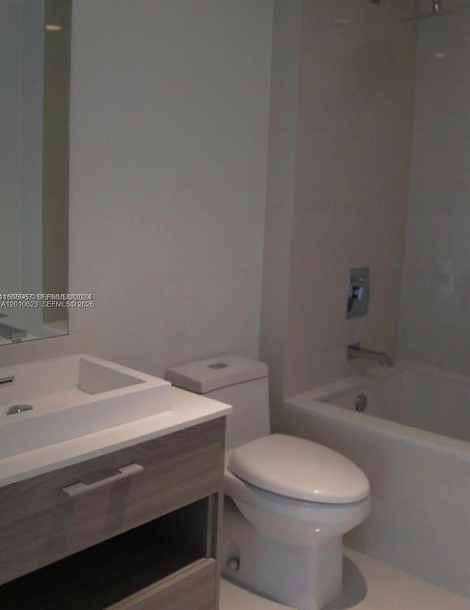 A bathroom features a white vanity, a toilet, and a bathtub with a shower head — 1300 S Miami Ave # 1908, Miami FL 33130, MIAMI, FL