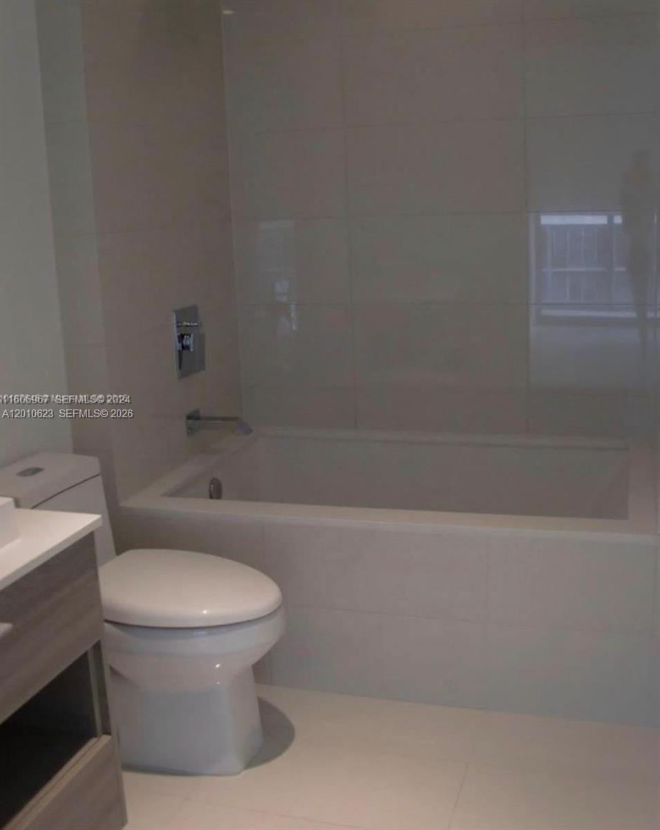 A bathroom features a white toilet, a built-in bathtub with light tile, and a vanity — 1300 S Miami Ave # 1908, Miami FL 33130, MIAMI, FL
