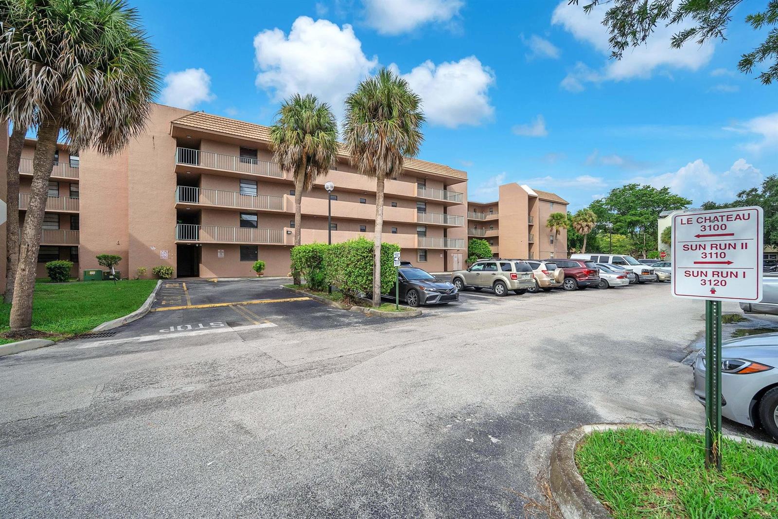 A multi-story apartment building with a parking lot and a directional sign in front — 3100 N Pine Island Road # 306, Sunrise FL 33351, SUNRISE, FL