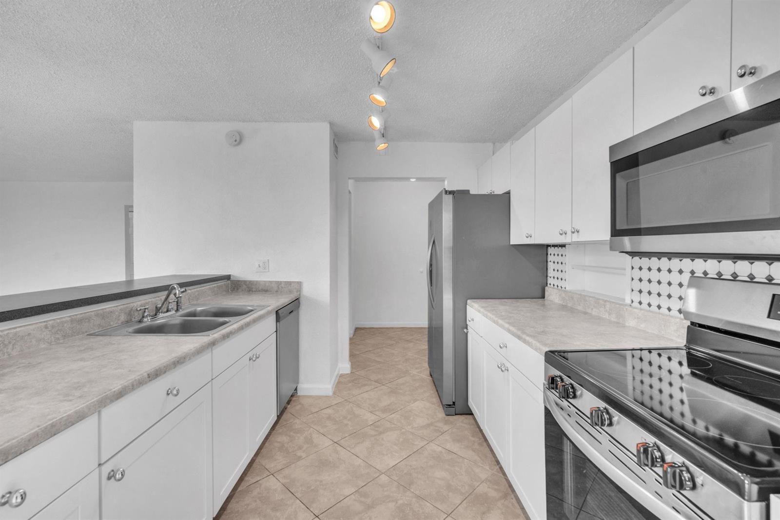 A kitchen with white cabinets, stainless steel appliances, grey countertops, and tile flooring — 3100 N Pine Island Road # 306, Sunrise FL 33351, SUNRISE, FL