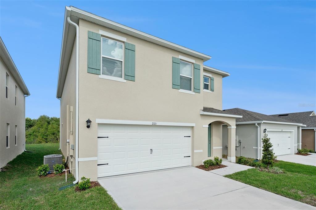 A two-story house with a beige stucco exterior, green shutters, and a two-car garage — 2113 WALNUT CREEK DRIVE, KISSIMMEE, FL