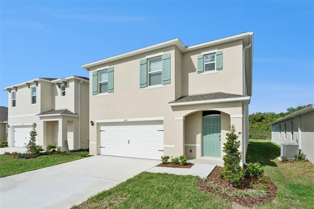 A two-story beige house with a white garage door and a light green front door — 2113 WALNUT CREEK DRIVE, KISSIMMEE, FL