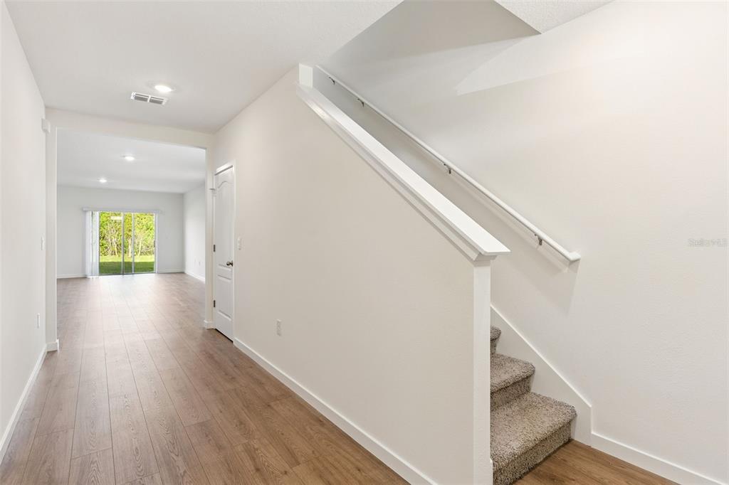 A hallway with wood-look flooring leads to a living area with stairs on the right — 2113 WALNUT CREEK DRIVE, KISSIMMEE, FL