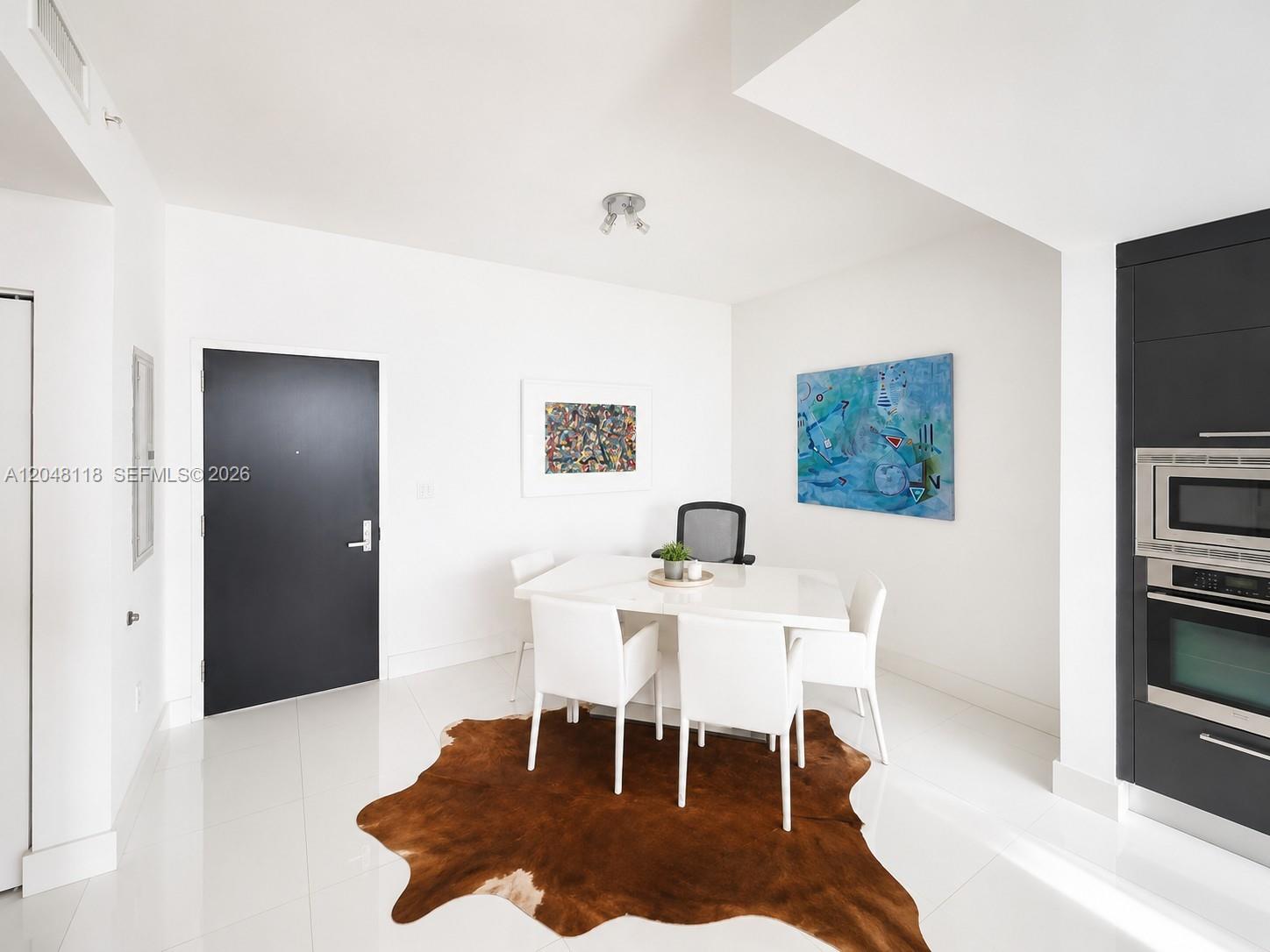 A dining area features a white table, four chairs, a cowhide rug, and modern artwork — 900 Biscayne Blvd # 5505, Miami FL 33132, MIAMI, FL