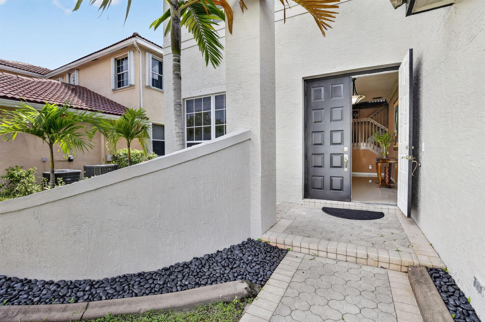 A paved walkway leads to the open front door of a stucco home with landscaping — 3535 SW 177th Avenue, Miramar FL 33029, MIRAMAR, FL