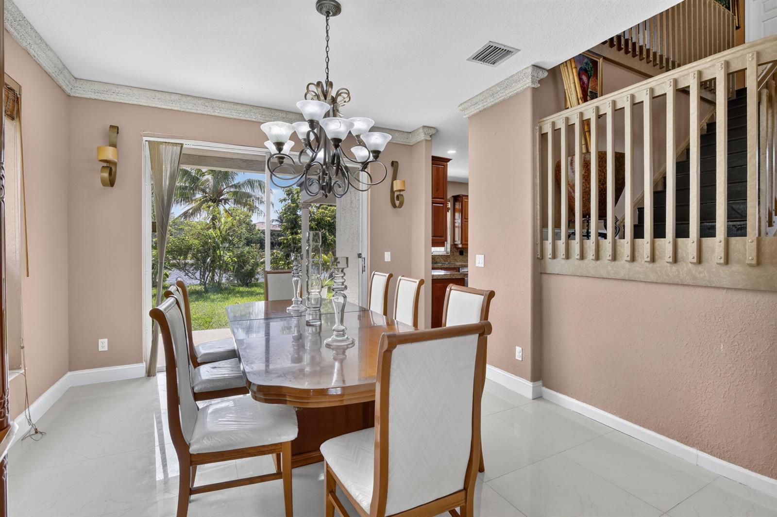 A dining room with a wooden table, chandelier, and sliding glass doors overlooking a backyard — 3535 SW 177th Avenue, Miramar FL 33029, MIRAMAR, FL