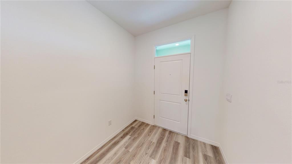 An entryway features white walls, wood-look flooring, and a white door with a transom window — 17280 BIGLEAF MAHOGANY LANE, LAND O LAKES, FL