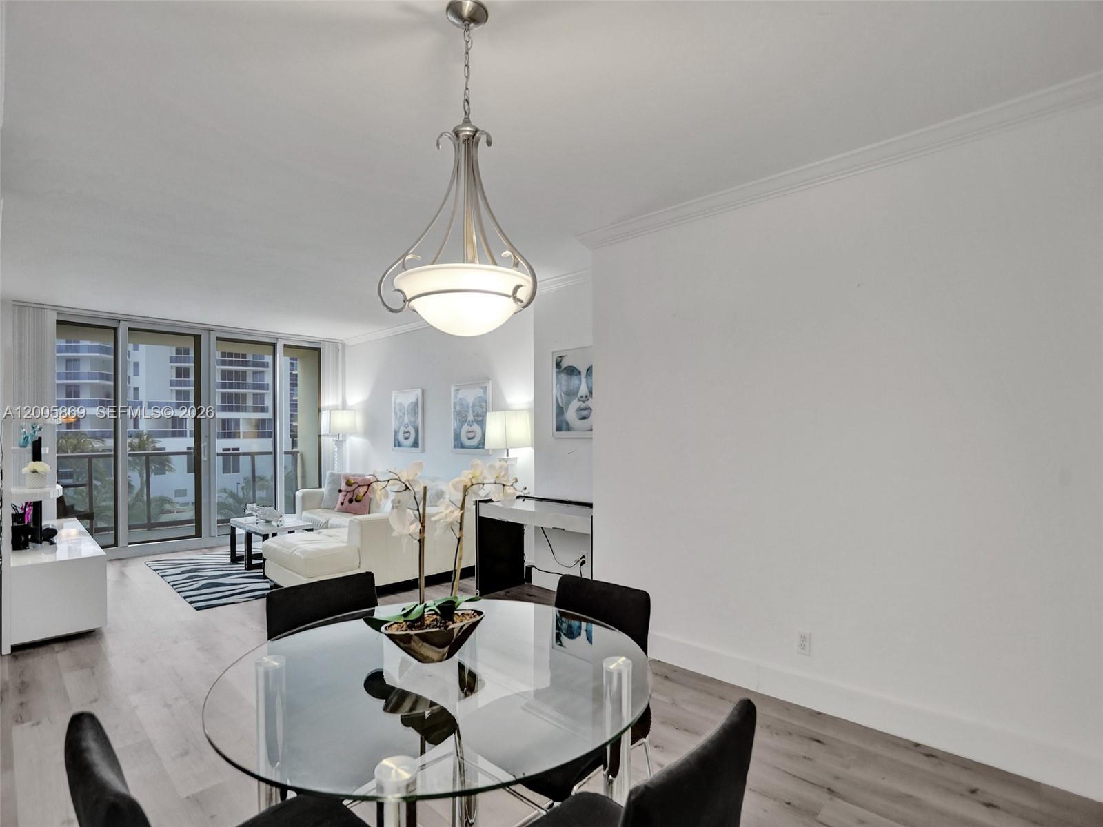 A dining area with a glass table and chandelier opens into a bright living room — 2501 S Ocean Dr # 415, Hollywood FL 33019, HOLLYWOOD, FL