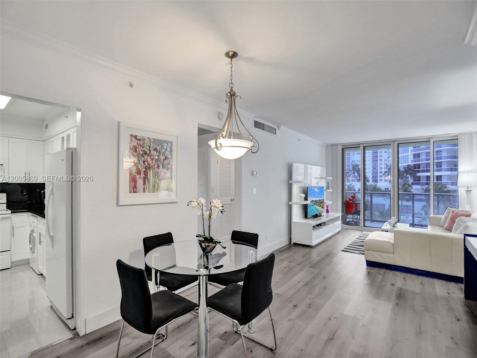 A dining area with a glass table and chairs sits beside a bright living room — 2501 S Ocean Dr # 415, Hollywood FL 33019, HOLLYWOOD, FL
