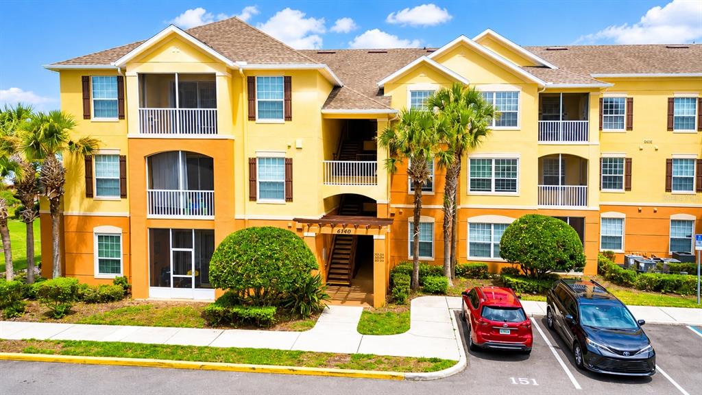 A three-story yellow apartment building with balconies and a parking lot in front — 6240 CONTESSA DRIVE UNIT 204, ORLANDO, FL