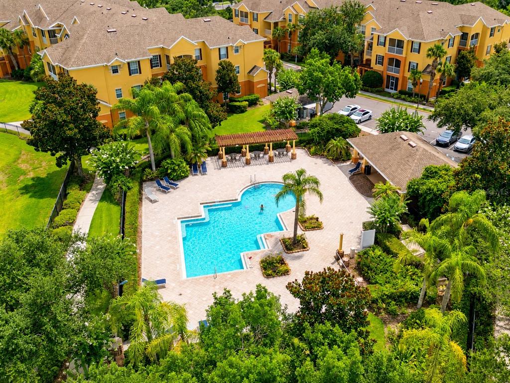 An aerial view of an apartment complex swimming pool with a pergola and surrounding landscaping — 6240 CONTESSA DRIVE UNIT 204, ORLANDO, FL