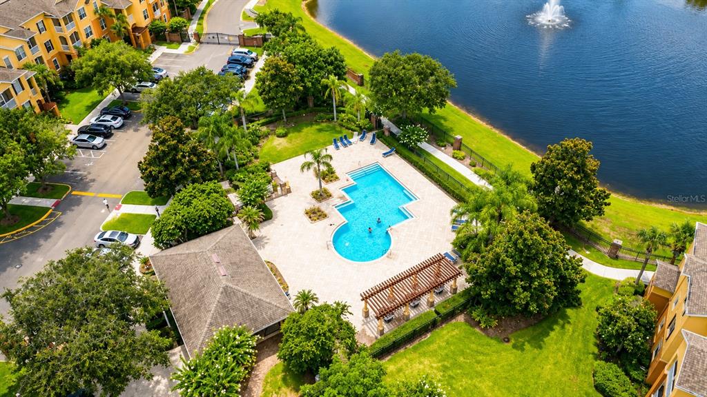 An aerial view shows a swimming pool, a pergola, and a lake with a fountain — 6240 CONTESSA DRIVE UNIT 204, ORLANDO, FL