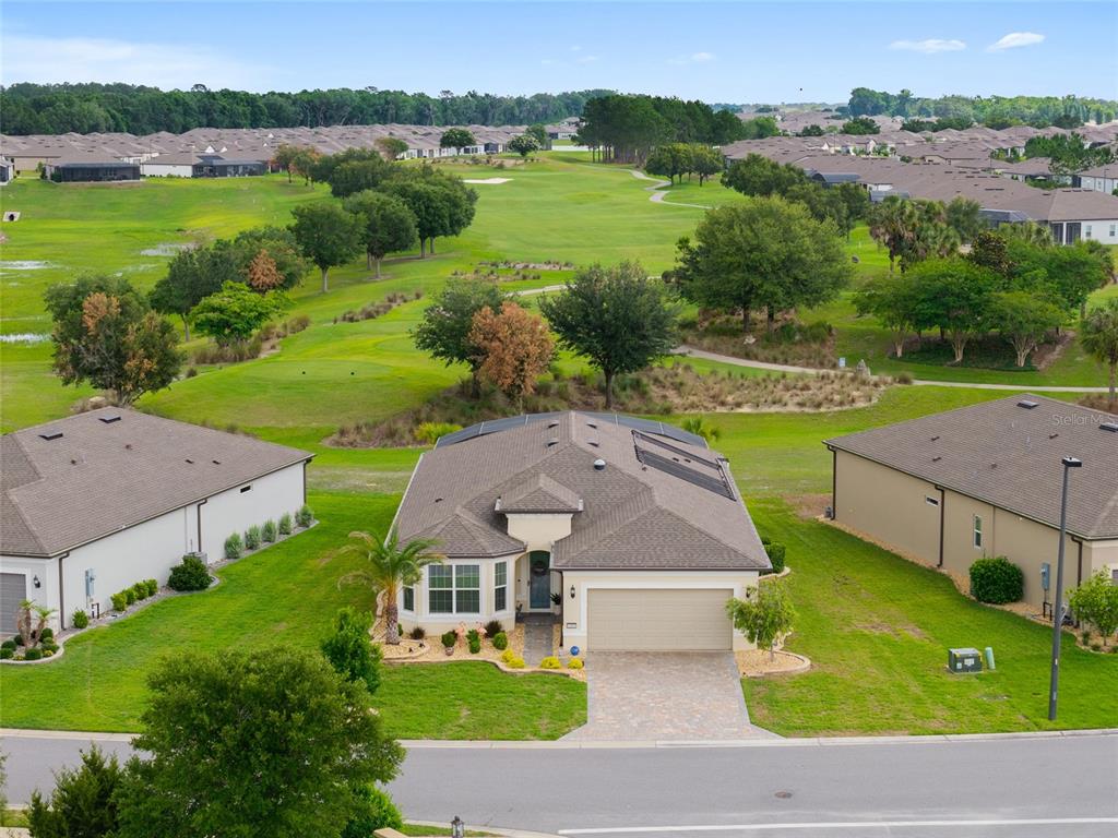 An aerial view shows a single-story house with a paved driveway facing a golf course — 5481 SW 92ND AVENUE ROAD, OCALA, FL
