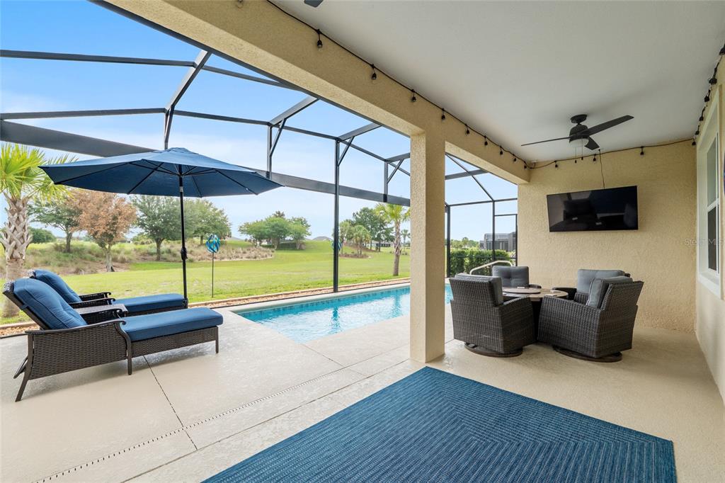 A covered patio features a swimming pool, lounge chairs, outdoor seating, and a mounted television — 5481 SW 92ND AVENUE ROAD, OCALA, FL