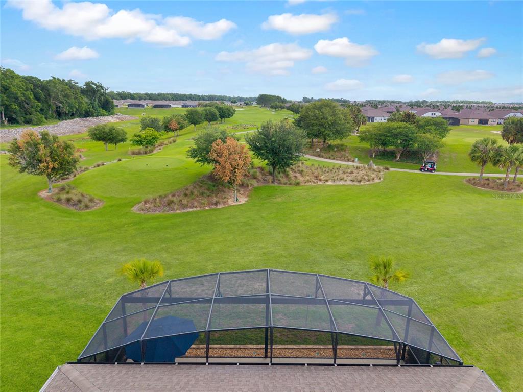 An aerial view shows a screened-in pool enclosure overlooking a golf course and residential neighborhood — 5481 SW 92ND AVENUE ROAD, OCALA, FL