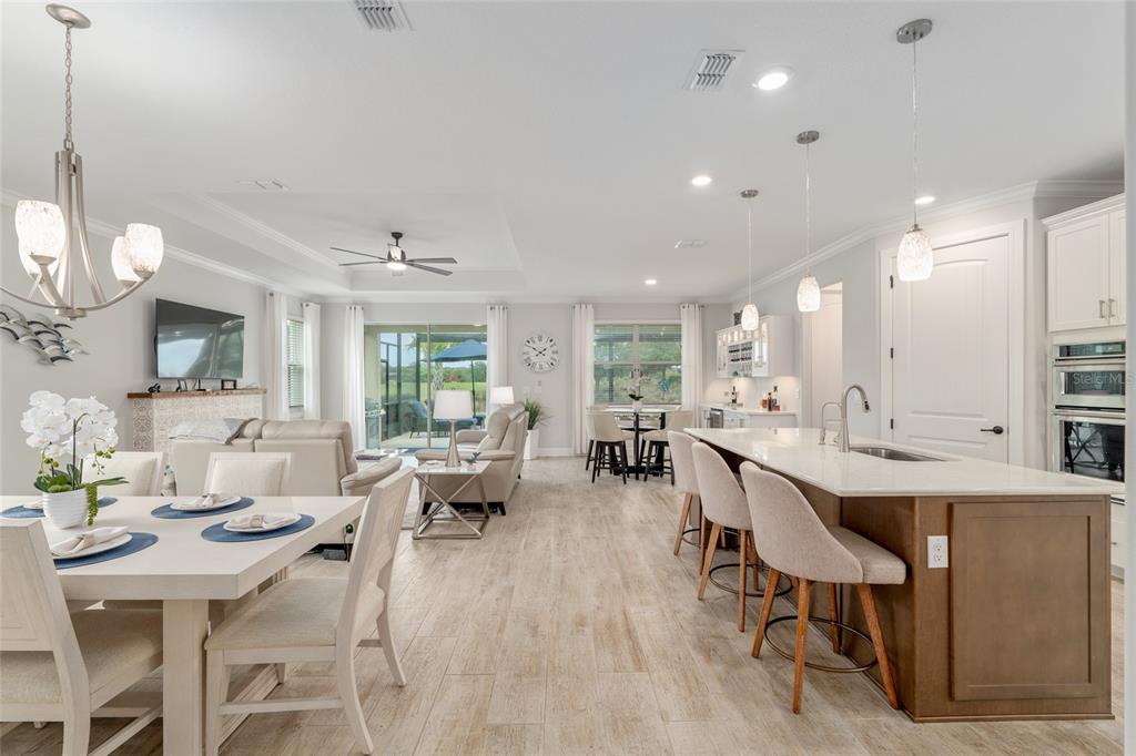 An open-concept kitchen and living area features a large island, dining table, and tile flooring — 5481 SW 92ND AVENUE ROAD, OCALA, FL