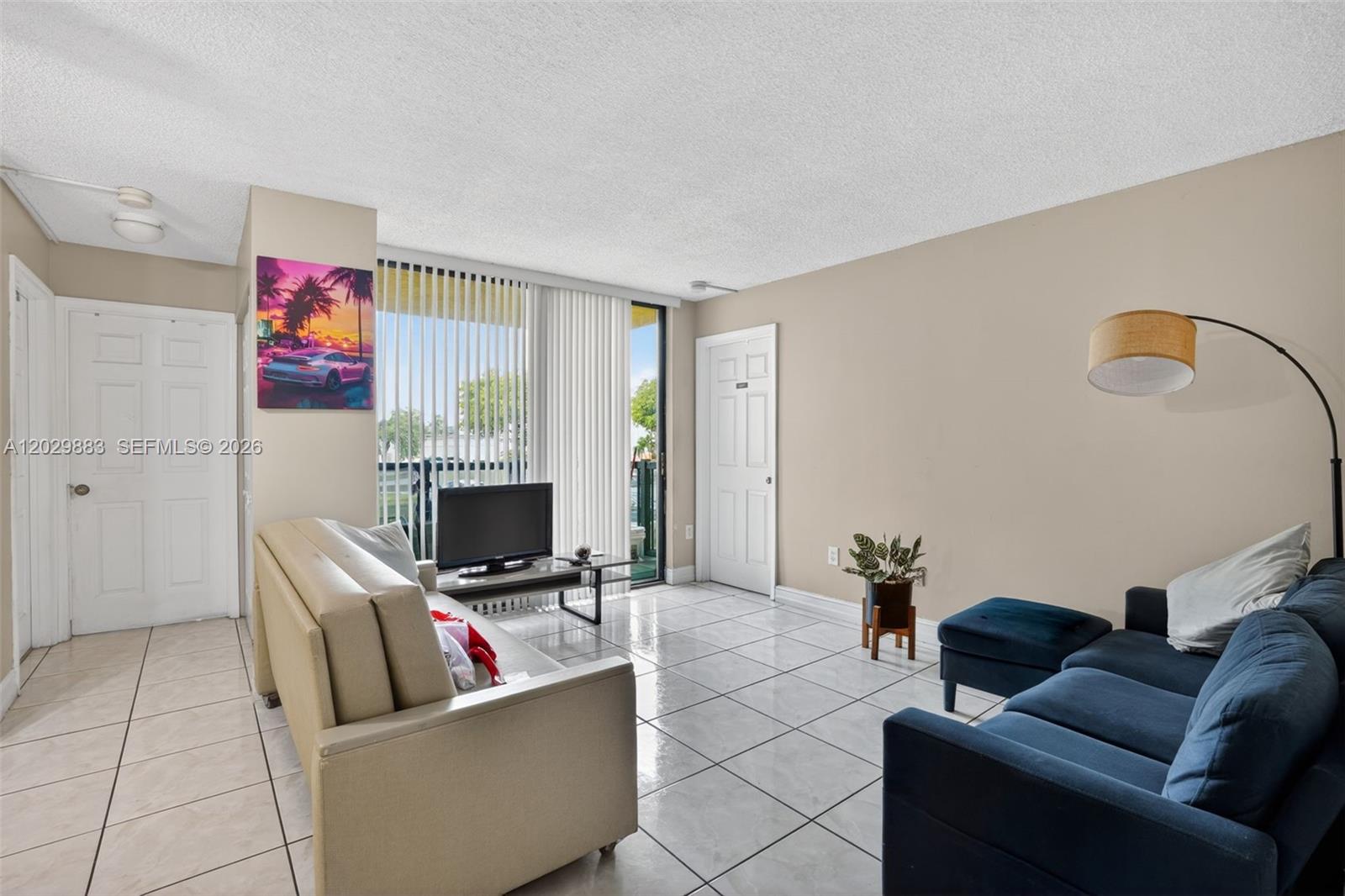 A living room features white tile flooring, two sofas, a television, and vertical window blinds — 11790 SW 18th St # 3, Miami FL 33175, MIAMI, FL