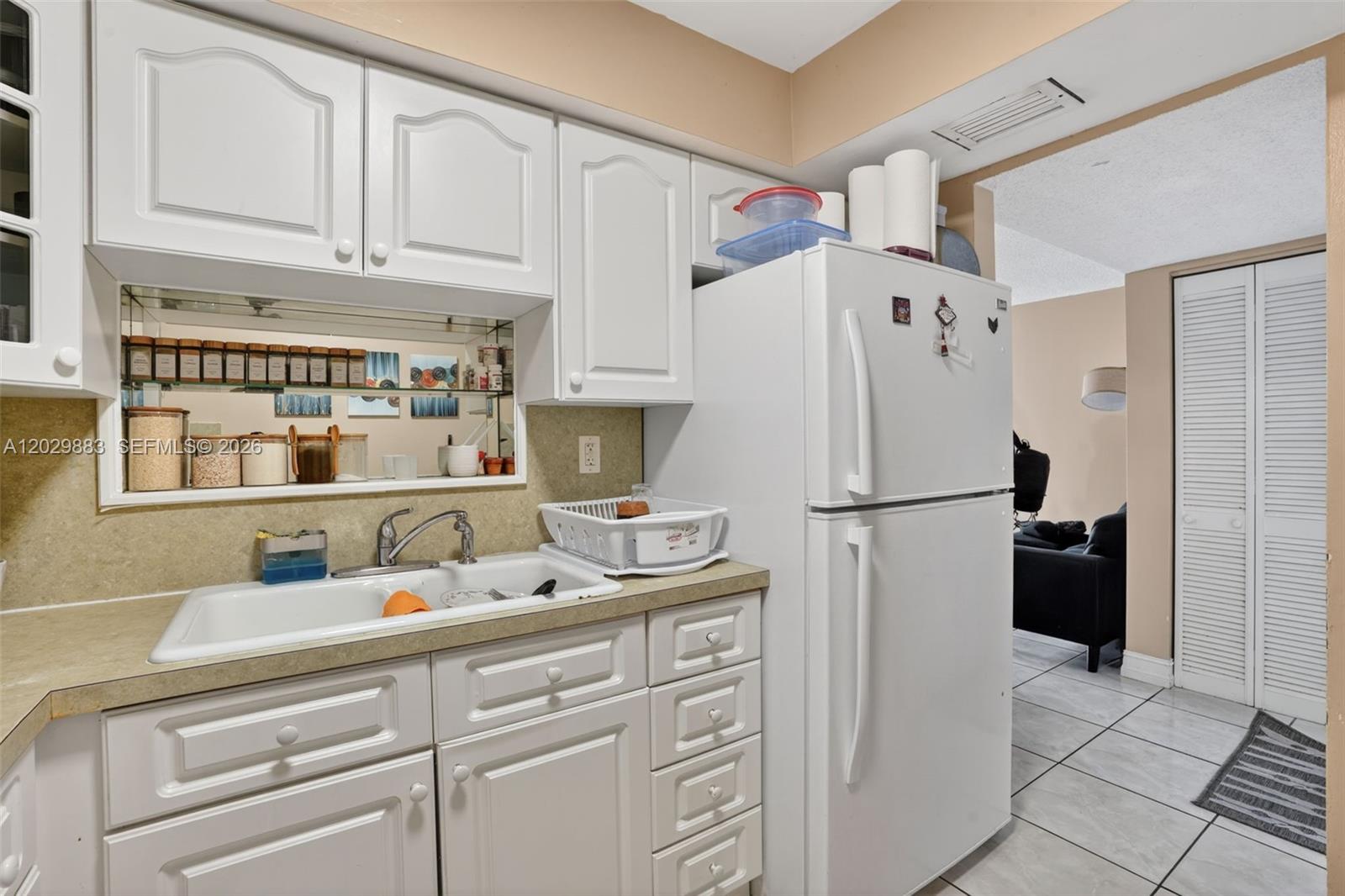 A kitchen features white cabinets, a white refrigerator, a sink, and a mirrored backsplash — 11790 SW 18th St # 3, Miami FL 33175, MIAMI, FL