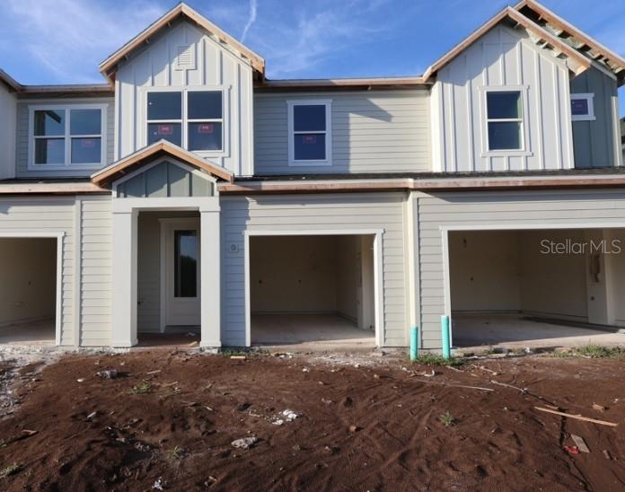 The exterior of a multi-unit townhouse construction site features light-colored siding and open garage bays — 6353 JENSEN VIEW AVENUE, APOLLO BEACH, FL