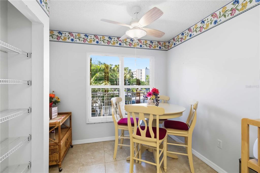 A dining area with a round table, four chairs, a ceiling fan, and floral wallpaper border — 3950 IRONWOOD CIRCLE UNIT 205, BRADENTON, FL
