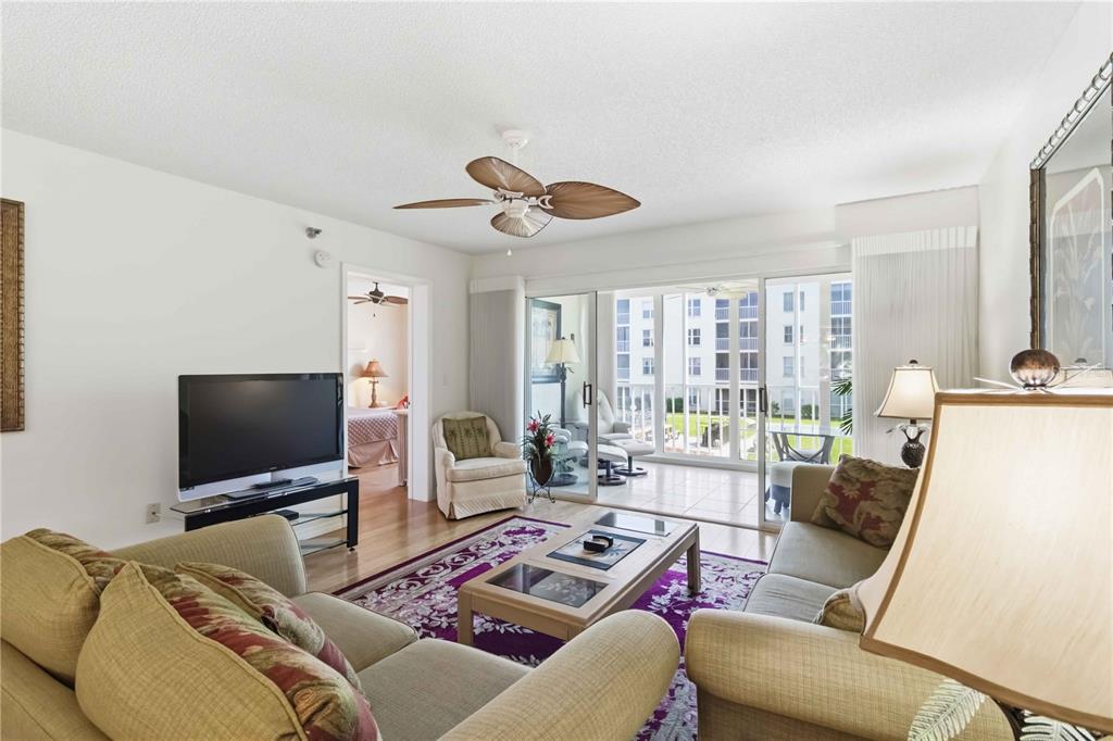 A living room with beige sofas, a purple rug, and sliding doors leading to a balcony — 3950 IRONWOOD CIRCLE UNIT 205, BRADENTON, FL