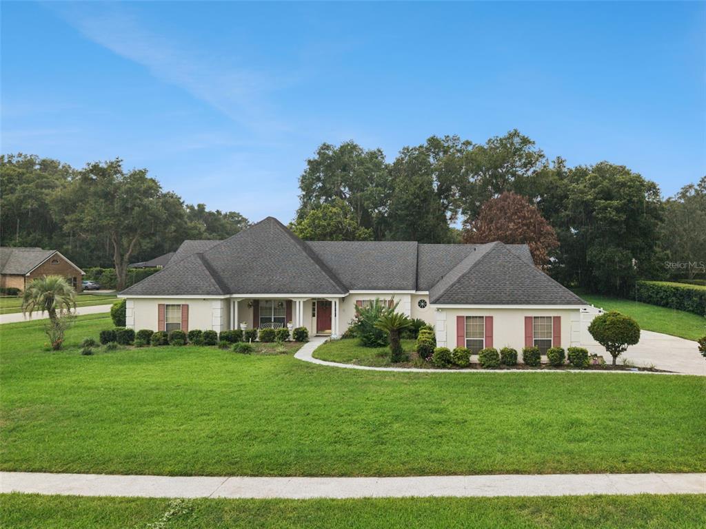 A single-story house with a gray shingled roof, beige stucco walls, and red shutters — 2512 TRYON PLACE, WINDERMERE, FL
