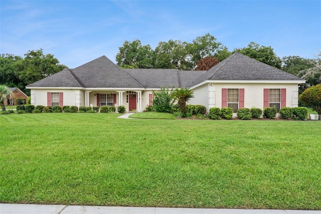 A single-story house with a red front door, dark shutters, and a large front lawn — 2512 TRYON PLACE, WINDERMERE, FL