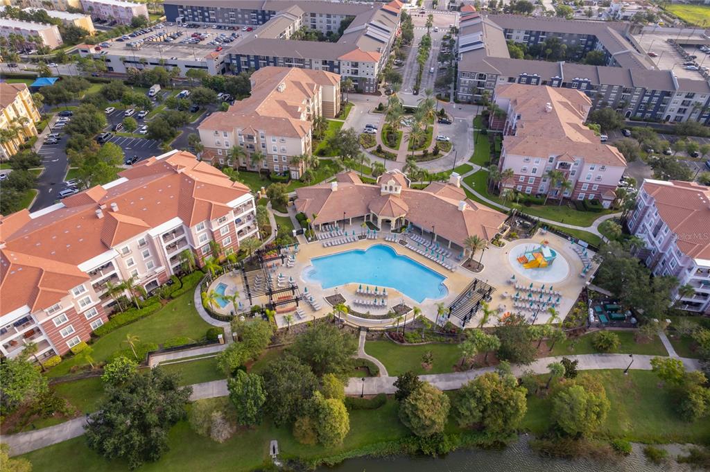 An aerial view of a large apartment complex featuring a central swimming pool and clubhouse — 5036 SHOREWAY LOOP UNIT 20705, ORLANDO, FL